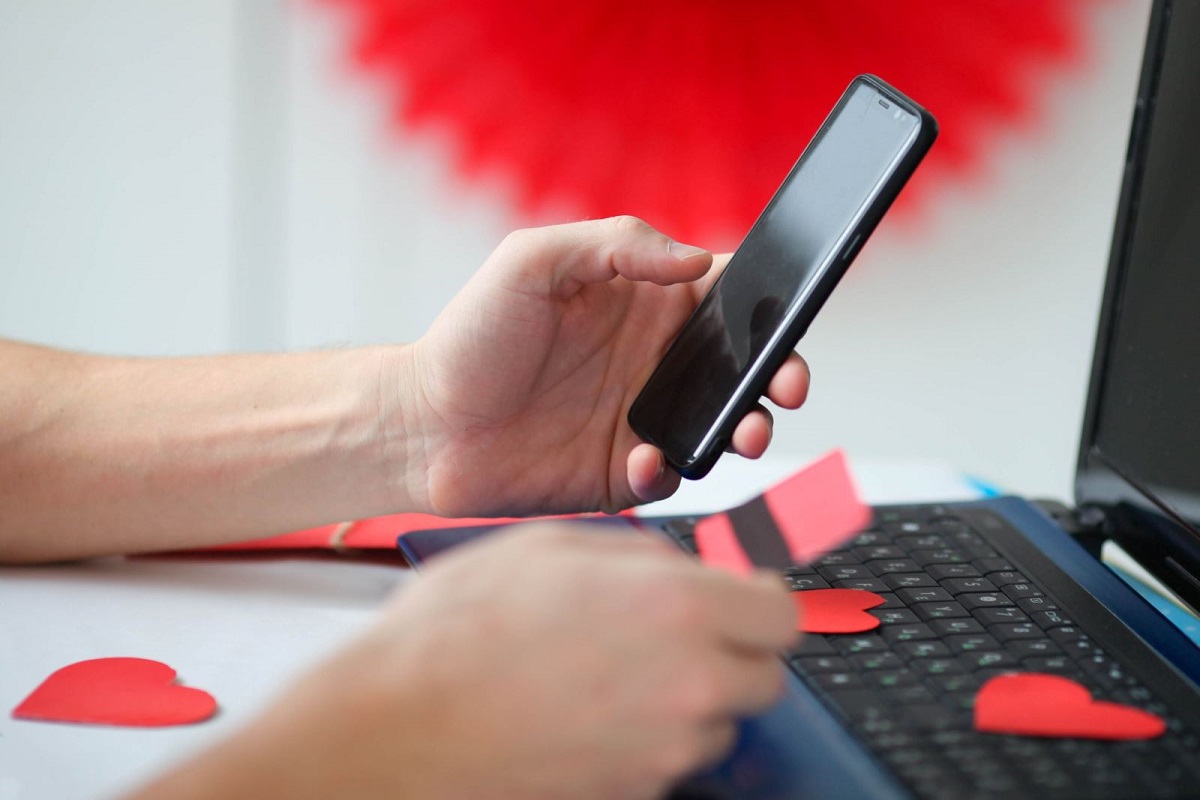 Person looking at phone and credit card in front of laptop