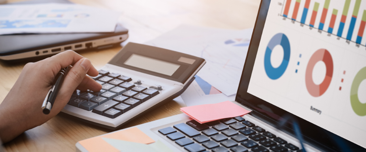 A close-up view of a person using a laptop with charts and a financial spreadsheet on the screen, representing the process of auditing business expenses and optimizing a budget.