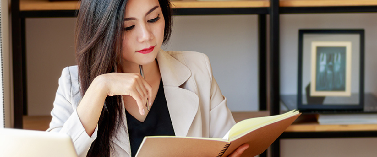 Image of Woman Reading Book at Her Desk