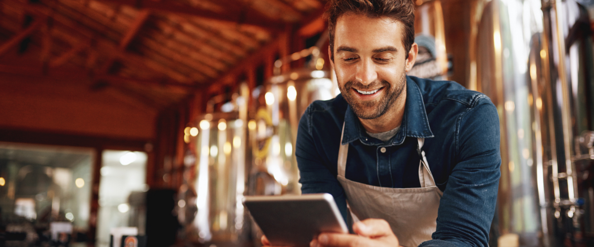 A Male Small Business Owner Looking At A Financial Statement At His Cafe