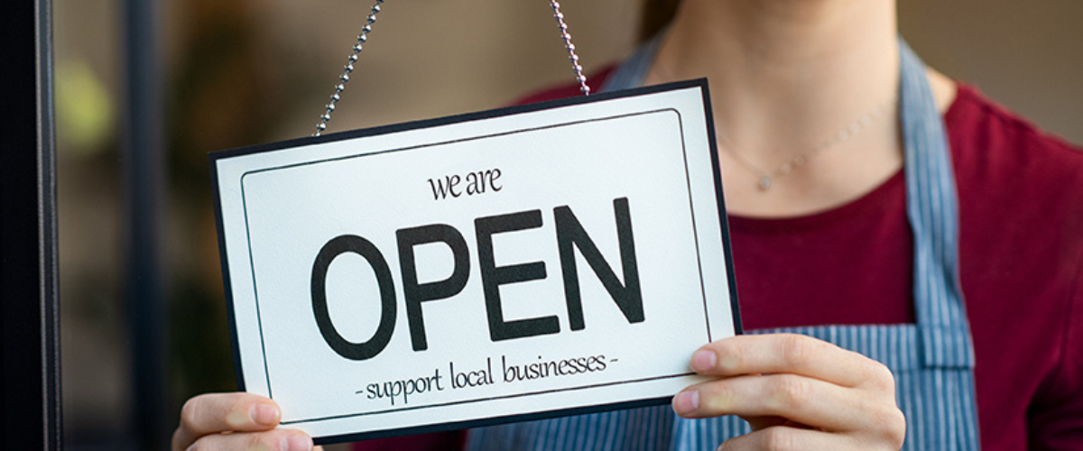 Image of Worker Hanging Up A 'We Are Open' Sign