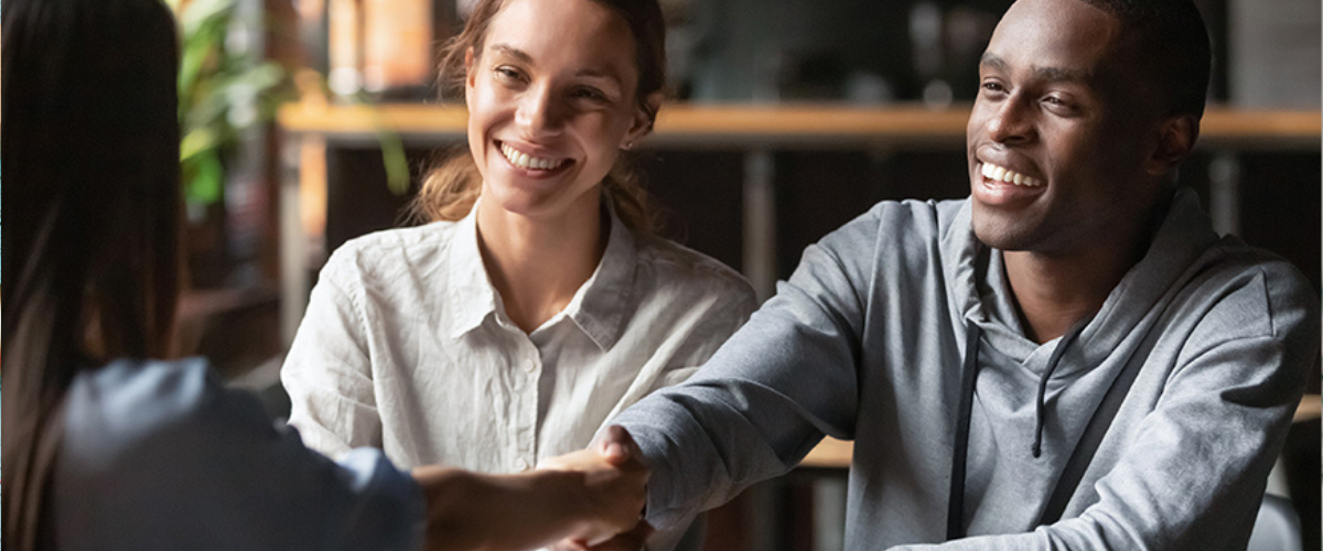 Image of People at Desk Shaking Hands.