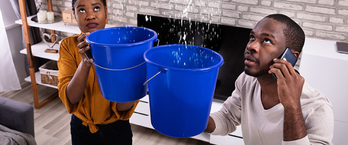 Image of Couple Holding Buckets to Catch Water from Ceiling